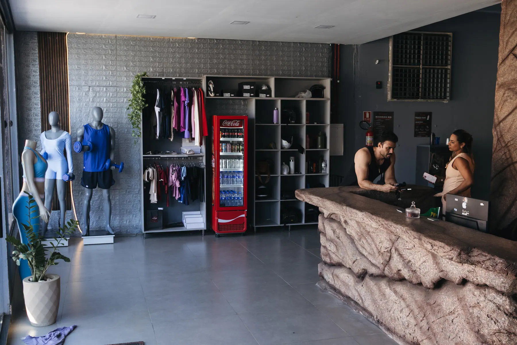 Recepção da TARG com balcão de atendimento, loja de roupas e geladeira de bebidas