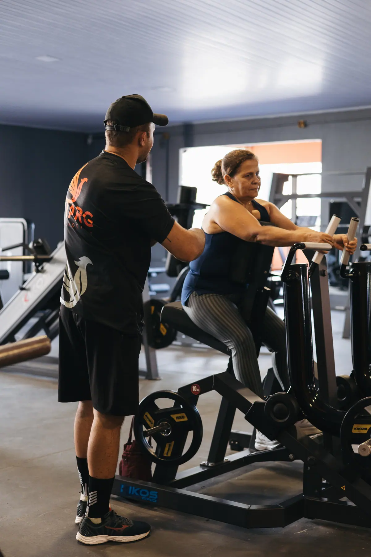 Instrutor corrigindo a postura de uma aluna durante o exercício no aparelho